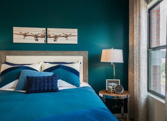 Bedroom With Bed And Side Table With Large Window At Union at Roosevelt Apartments In Phoenix, AZ