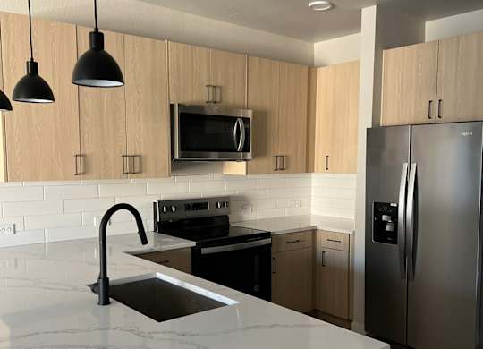 a kitchen with a marble counter top and a stainless steel refrigerator