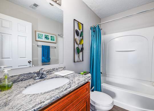 A bathroom with a marble countertop and a white bathtub.