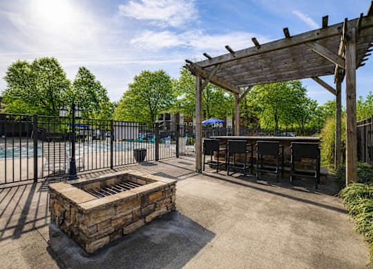 A patio area with a fire pit and a pergola.