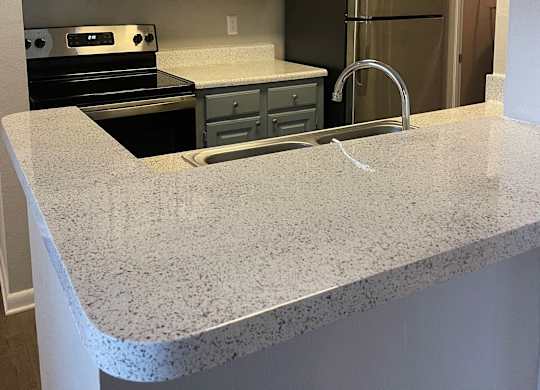 a kitchen with granite counter tops and stainless steel appliances at Aqua Bay Apartments in Naples, FL 34116