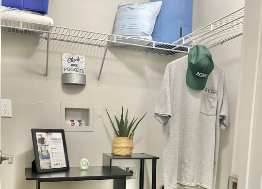 a small room with a table and shelves and a shirt hanging on the wall