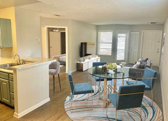 a living room and kitchen with a glass table and chairs at Aqua Bay Apartments in Naples, FL 34116