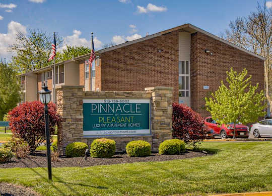 The image shows a building with a sign that reads "Pinnacle Pleasant Luxury Apartment Homes".