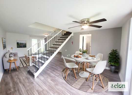 A dining room with a table set for four and a staircase.