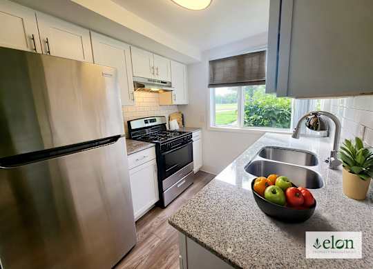 A modern kitchen with a stainless steel refrigerator and a bowl of fruit on the counter.