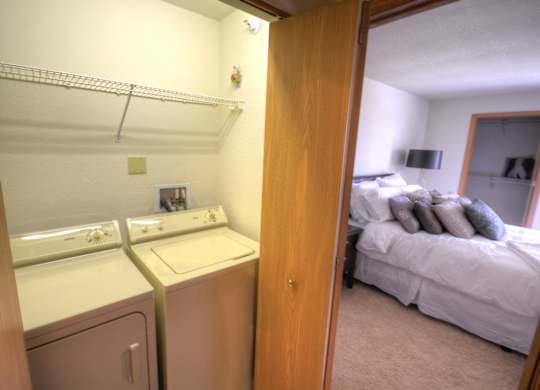 a bedroom with a washer and dryer next to a bed