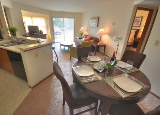 the dining room and living room of a condo with a dining table and a kitchen
