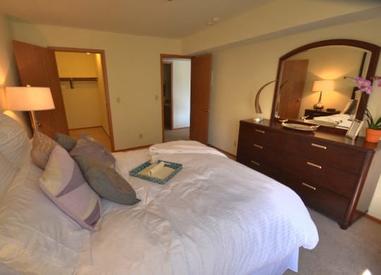 a bedroom with a large bed and a dresser with a mirror