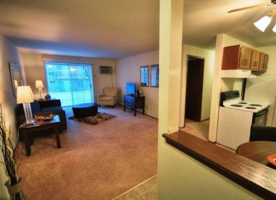 an open living room and a kitchen with a stove and refrigerator