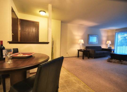 a living room and dining room with a table and a bottle of wine