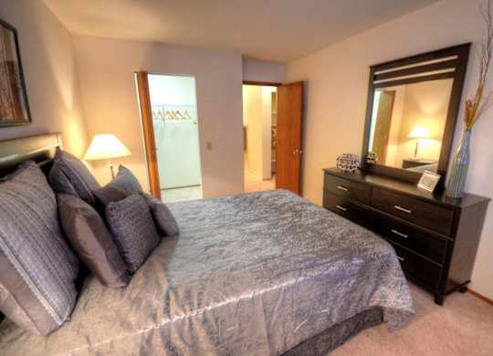 a bedroom with a large bed and a dresser and a bathroom