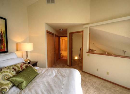 a bedroom with a bed and a hallway to a bathroom