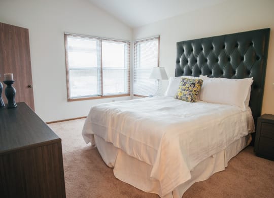 a bedroom with a bed and a dresser and windows