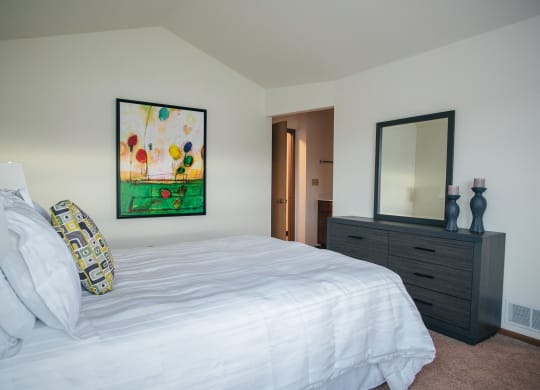 a bedroom with a white bed and a painting on the wall