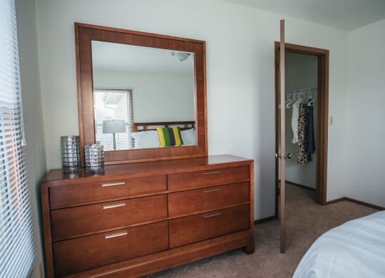 a dresser with a mirror in a bedroom with a closet