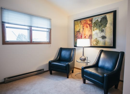 a living room with two leather chairs and a painting on the wall