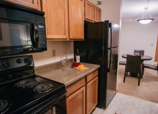 a kitchen with black appliances and a counter with a bottle of wine