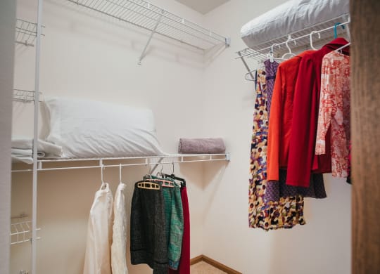 a bedroom with a bunk bed and a closet with clothes and a rack with clothes