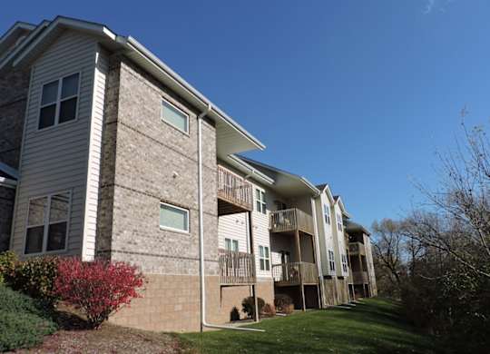 an apartment building with a grass yard and a blue sky