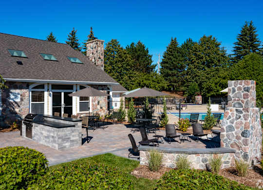 Clubhouse with a stone chimney and a patio with chairs and a table.