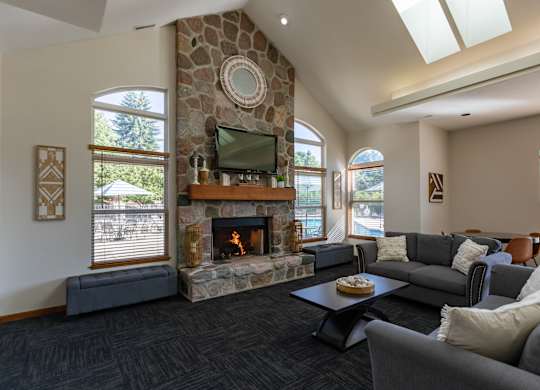 A living room with a stone fireplace and a flat screen TV.