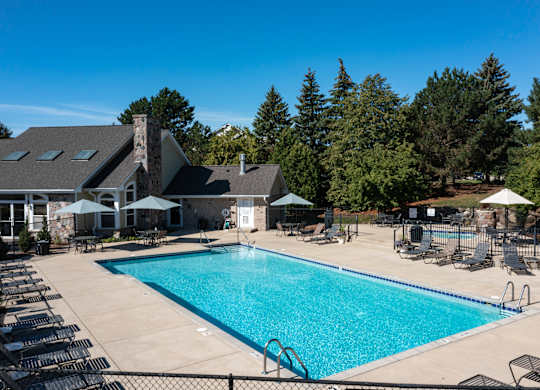A large swimming pool surrounded by lounge chairs and umbrellas.