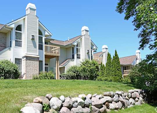 Apartments  with a white exterior and a stone wall in front.