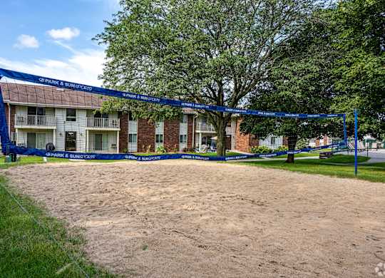 A volleyball net is set up in the sand in front of a brick building.