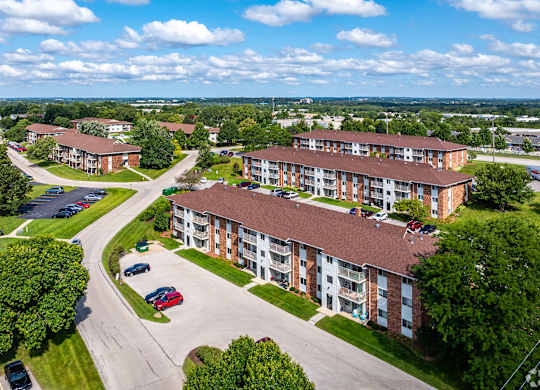 A large apartment complex with a parking lot in front.