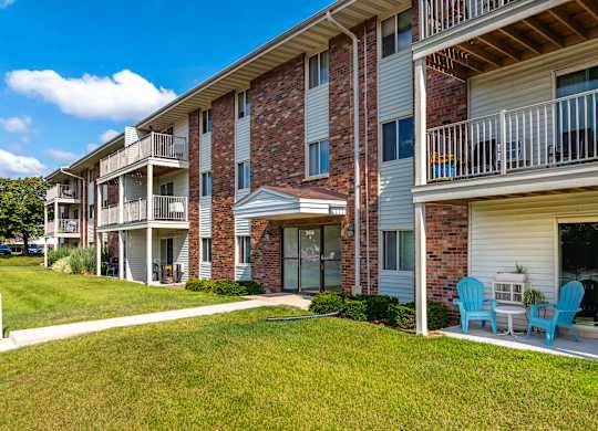 Apartment building with blue chairs on the balcony.