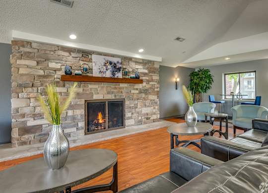 A living room with a stone fireplace and a grey sofa.