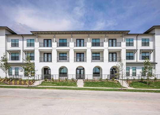 a large white building with a blue sky in the background lots of windows and arched entryways