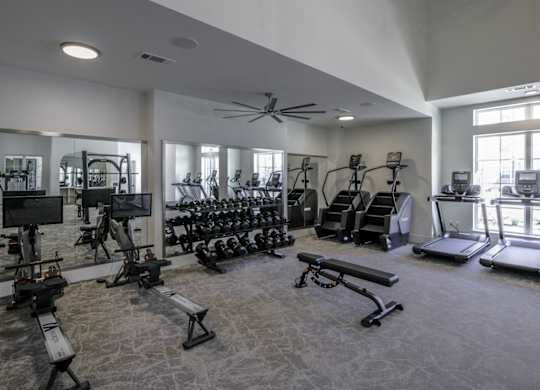 a gym with weights and cardio equipment in a building with windows