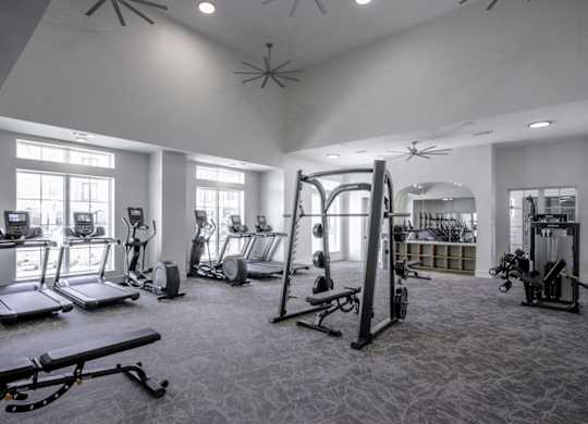 a gym with cardio equipment and weights in a building with windows