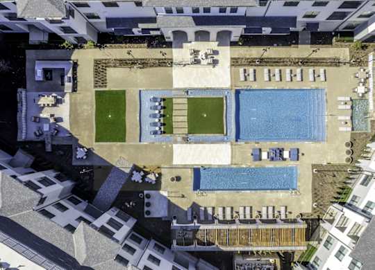 an aerial view of a building with a pool and grass