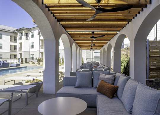 a lounge area with a couch and tables and a swimming pool