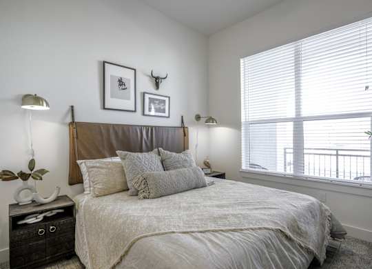 a bedroom with a large bed and two windows