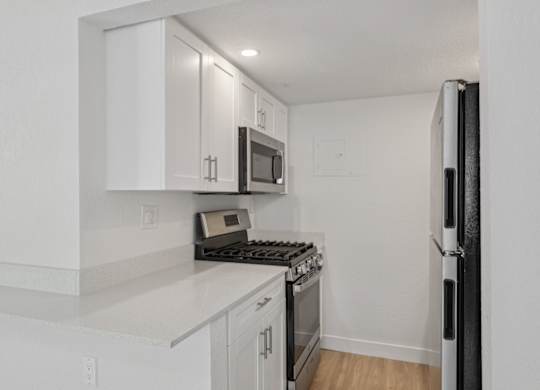 A kitchen with white cabinets and sleek stainless steel appliances at Haven on Canal