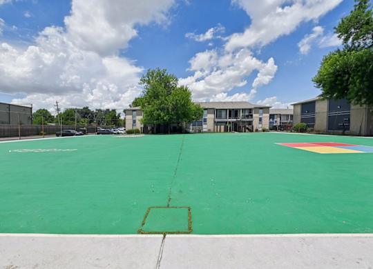 A basketball court with a green surface and a white line in the middle.