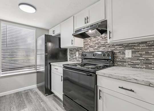 A kitchen with black appliances and white cabinets.
