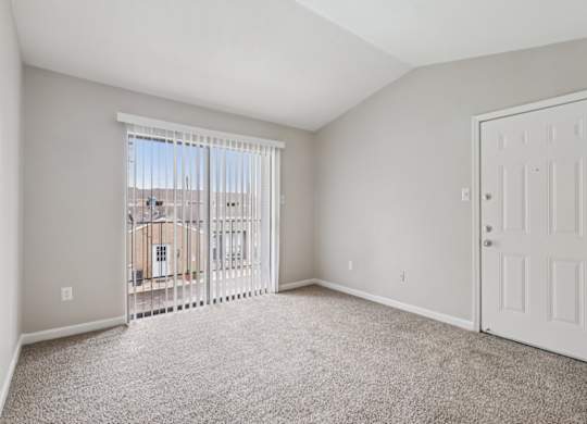 A room with a white door and a window with a view of a building outside.