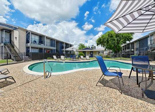 A pool surrounded by chairs and umbrellas in a residential area.