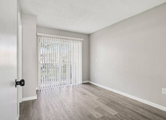 A room with a door and a window with blinds.