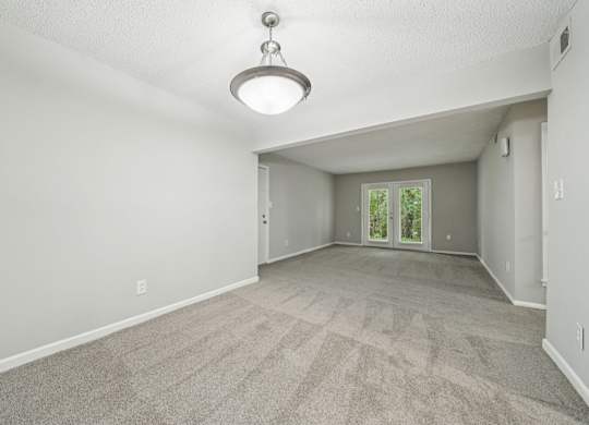 A spacious room with a carpeted floor and a ceiling light.