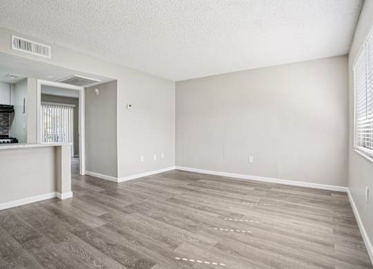 A room with a wooden floor and a window with blinds.