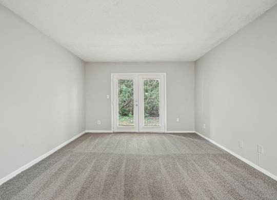 A room with a carpeted floor and a sliding glass door leading outside.