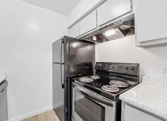 A black stove and refrigerator in a kitchen.