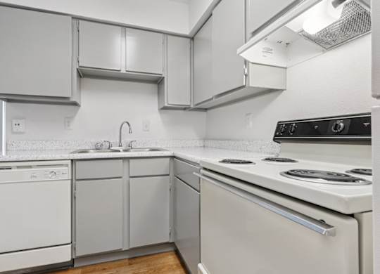 A white kitchen with a stove top oven and a dishwasher.