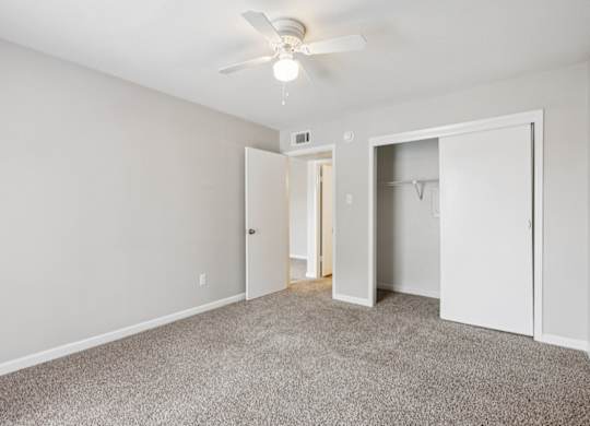 A room with a ceiling fan and carpeted floor.